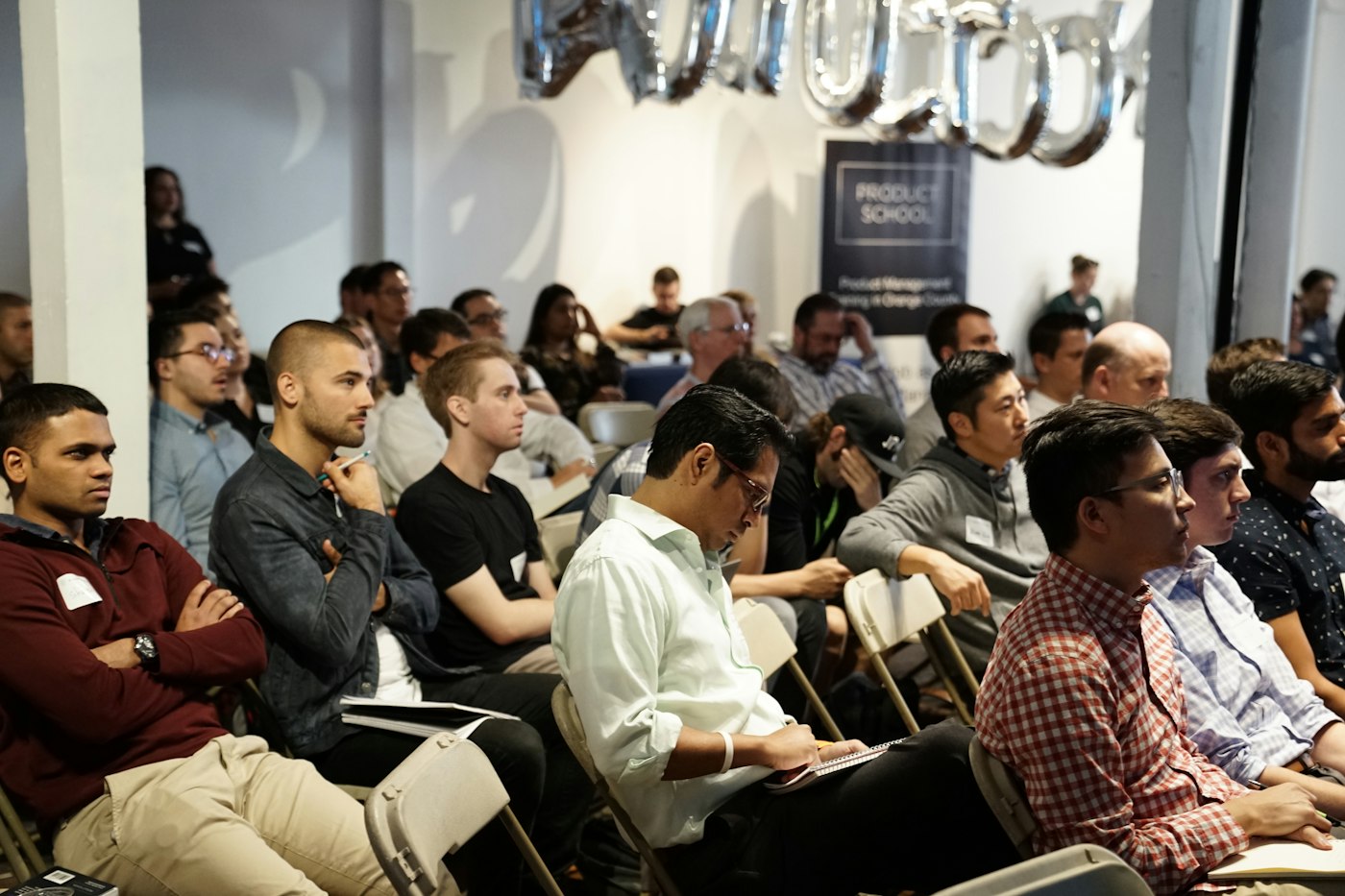 People sitting in an audience listening to a presentation at a conference 